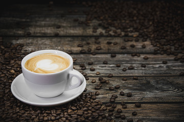cup of coffee latte with beans on brown wooden background 