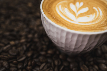 close up cup of coffee latte with beans on brown wooden background 