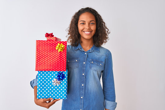 Young brazilian woman holding birthday gifts standing over isolated white background with a happy face standing and smiling with a confident smile showing teeth