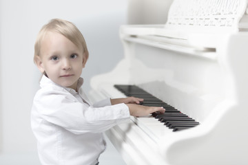 Little boy in studio near white piano.