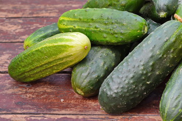 Heap of green raw cucumber on old wooden plank surface