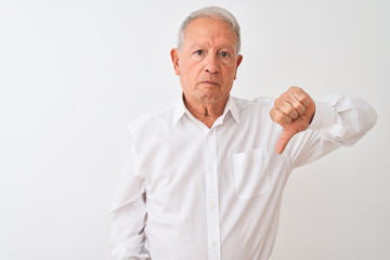 Senior grey-haired man wearing elegant shirt standing over isolated white background looking unhappy and angry showing rejection and negative with thumbs down gesture. Bad expression.