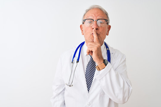 Senior grey-haired doctor man wearing stethoscope standing over isolated white background asking to be quiet with finger on lips. Silence and secret concept.