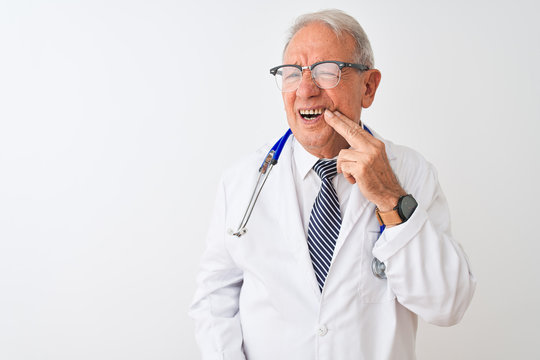 Senior grey-haired doctor man wearing stethoscope standing over isolated white background touching mouth with hand with painful expression because of toothache or dental illness on teeth.