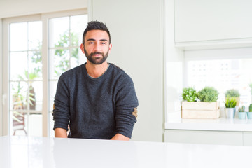 Fototapeta premium Handsome hispanic man wearing casual sweater at home Relaxed with serious expression on face. Simple and natural looking at the camera.