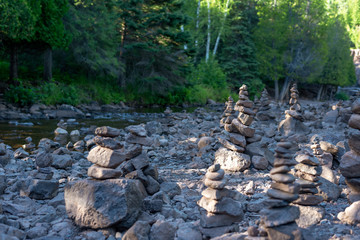 rows of stone cairns along peaceful forest stream