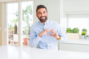 Handsome hispanic business man smiling in love showing heart symbol and shape with hands. Romantic concept.