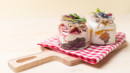Raspberry cakes in glass jar with fresh fruit and cream cheese on a red napkin.