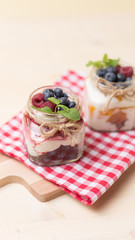 Raspberry cakes in glass jar with fresh fruit and cream cheese on a red napkin.