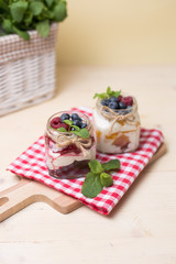 Raspberry cakes in glass jar with fresh fruit and cream cheese on a red napkin.