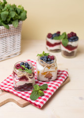Raspberry cakes in glass jar with fresh fruit and cream cheese on a red napkin.