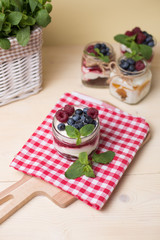 Raspberry cakes in glass jar with fresh fruit and cream cheese on a red napkin.