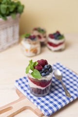 Raspberry cakes in glass jar with fresh fruit and cream cheese on a blue napkin.