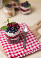Raspberry cakes in glass jar with fresh fruit and cream cheese on a red napkin.