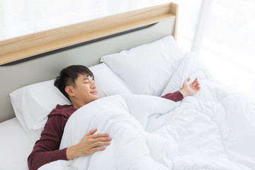 Asian man lying on bed, he slept deep in bedroom..