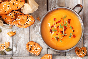 Bowl of pumpkin cream soup on rustic wooden background