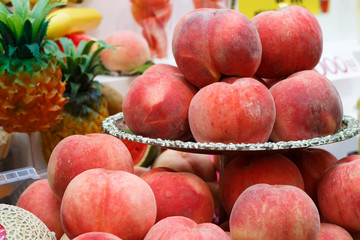 Many ripe peaches on a plate close-up, front view