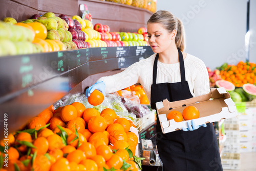 Salesgirl arranging goods in greengrocery