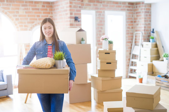 Beautiful asian young woman holding boxes, smiling happy moving to a new home