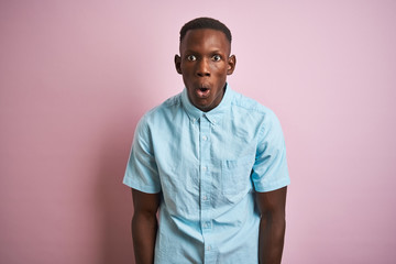 African american man wearing blue casual shirt standing over isolated pink background afraid and shocked with surprise expression, fear and excited face.