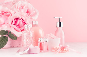 Different skin care products with romantic roses bouquet on girlish elegant pink pastel background with copy space.