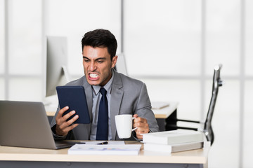 Businessman uses tablet computer, drinking coffee..