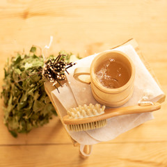 Pampering and relaxing in the sauna. Accessories for a steam room, wooden furniture, a bath broom and water in a mug.