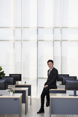 Businessman sitting on table in office..