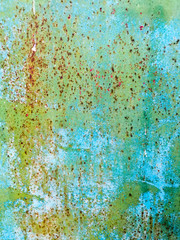 Old iron wall with scratches and rust covered with blue and green paint. Abstract background.