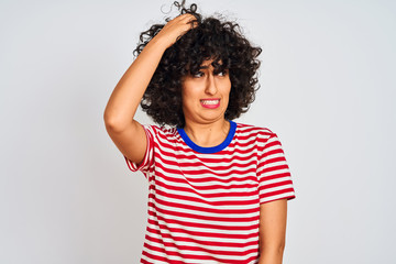 Young arab woman with curly hair wearing striped t-shirt over isolated white background confuse and...