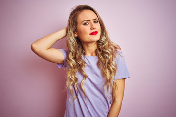 Young beautiful woman wearing purple t-shirt standing over pink isolated background confuse and wonder about question. Uncertain with doubt, thinking with hand on head. Pensive concept.