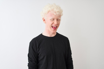 Young albino blond man wearing black t-shirt standing over isolated white background sticking tongue out happy with funny expression. Emotion concept.