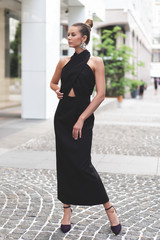 black evening womens dress on beautiful slender European model. Posing on street