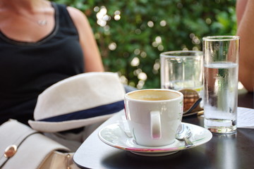 Midsection of two women sitting in the restaurant with cup of coffee in the foreground
