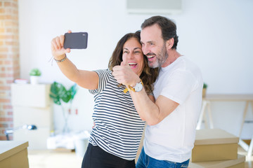 Middle age senior romantic couple taking a selfie picture with smartphone smiling happy for moving to a new house, making apartment memories