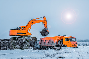 Excavator is loading excavation to the truck. Excavators hydraulic are heavy construction equipment consisting of a boom, dipper or stick , bucket and cab on a rotating platform.