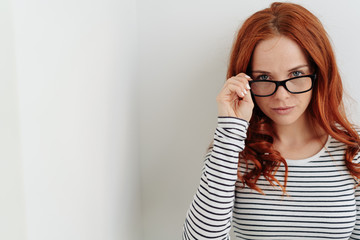 Thoughtful young woman peering over her glasses