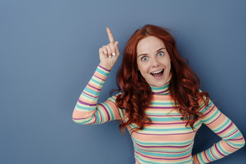 Cheerful woman pointing up against blue background