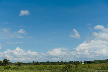 Bright sky filled with white clouds and green field