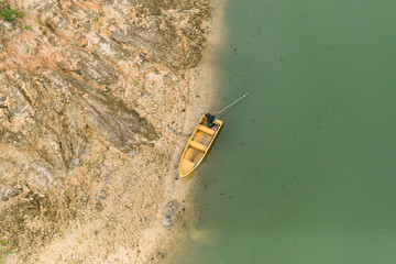 The yellow boat is parked on the green water shore.