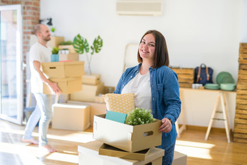 Young couple moving to new apartment, beautiful woman moving cardboard boxes and smiling happy