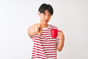 Young chinese man drinking a cup of coffee standing over isolated white background pointing with...