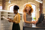 Red-haired young businesswoman sanding at cashier desk