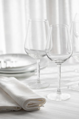 Table setting white and grey colour. Empty glasses and plates set with napkin and cutlery. Restaurant interior background.