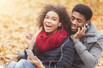 Happy couple enjoying fall in the park, listening music