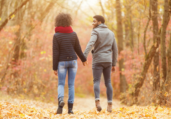 Afro couple in love holding hands and walking in park