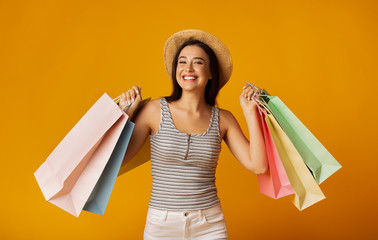 Smiling Girl Holding Colorful Shopping Bags On Yellow Studio Background