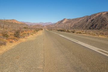 A motorway leads through an arid landscape to the hills image in landscape format with copy space