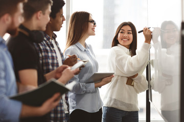 Girl showing answers on whiteboard in classroom