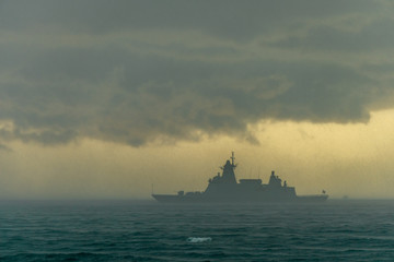 Modern stealth frigate sails in the storm. silhouette style.